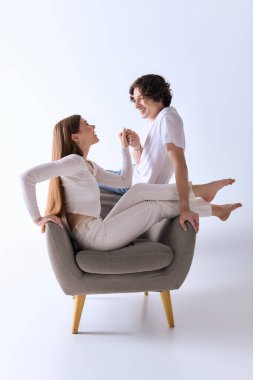 Mutlu bir çift, gri bir stüdyoda neşeli bir şekilde poz veriyor, gülümsüyor ve sevgisini paylaşıyor..