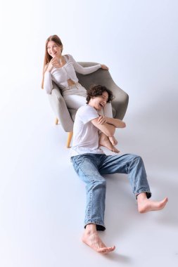 Mutlu bir çift, açık gri bir stüdyoda, aşk ve tarz saçan neşeli pozlardan hoşlanır..