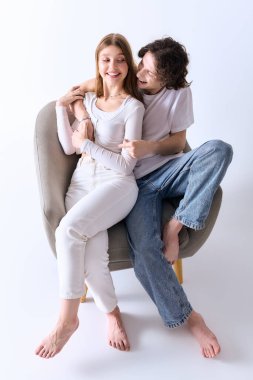 Mutlu çift şık, gri bir stüdyoda sarılıyor, sıcaklığı ve sevgiyi birlikte yayıyorlar..