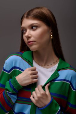 Şık bir genç kadın zarif bir şekilde poz veriyor. Gri bir arkaplana karşı..