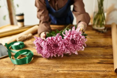 Tutkulu bir çiçekçi dükkanındaki müşteriler için canlı pembe çiçekler hazırlar..