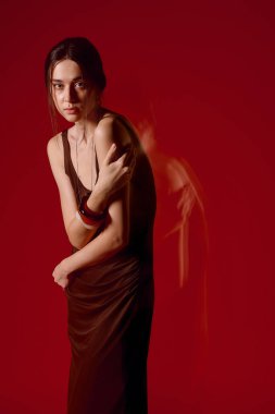 Şık elbiseli güzel bir kadın canlı renklere karşı zarifçe poz verir..