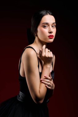 Şık bir kadın, kendine güven ve cazibe saçan siyah bir elbise içinde zarifçe poz verir..