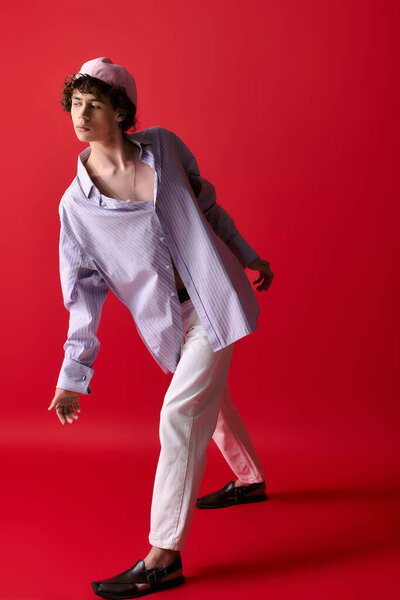 Стильный молодой человек позирует в свободной рубашке и модных туфлях, выставляя напоказ свое чувство стиля.