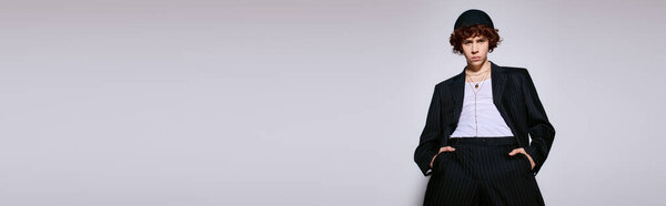 Young man in trendy outfit stands confidently against a minimalist backdrop, savoring the moment.