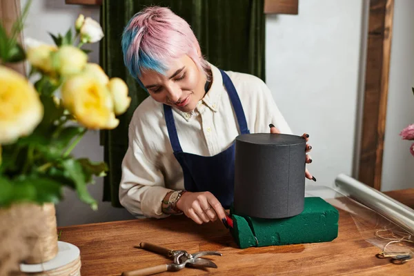 Genç çiçekçi çiçekçi, çiçekçi köpüğü keser, dükkanında büyüleyici bir düzenleme için hazırlanır..