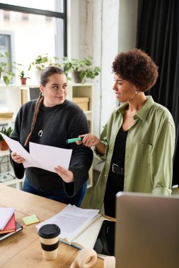 İki kadın yönetici çağdaş ofis ortamında planları tartışıyor ve fikirlerini paylaşıyor..