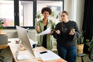İki kadın yönetici, bitkilerle dolu canlı bir ofiste planlama seansına katılıyor..