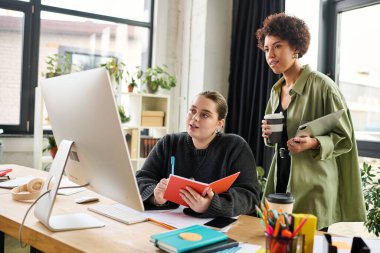 Modern bir çalışma alanında fikirleri paylaşan iki kadın yaratıcılığı ve takım çalışmasını teşvik ediyor..
