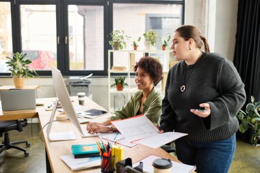 Young plus size woman and African American colleague create a welcoming work atmosphere.