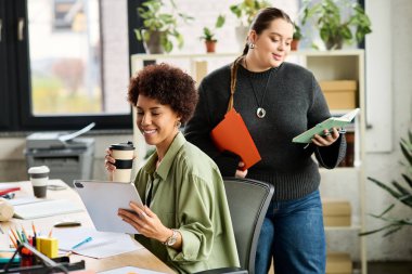 İki kadın yönetici, parlak ve modern ofis ortamında canlı bir iş görüşmesi yapıyorlar..