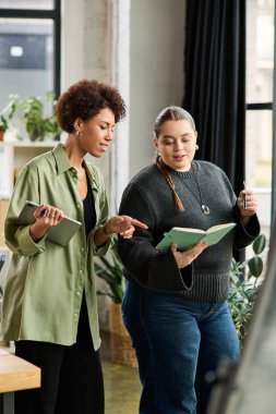 İki kadın yönetici, şık bir ofiste belgeleri incelerken işbirliği yapıyor ve tartışıyorlar..