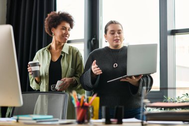 İki genç bayan yönetici şık bir ofiste çalışırken verimli bir konuşma yapıyorlar..