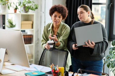 Genç ve iri yarı bir kadın ve siyah meslektaşı iş yerinde takım çalışması ve çeşitliliği tartışıyor..