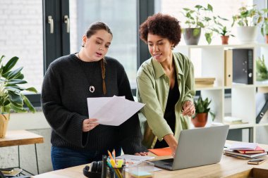 Meslektaşlar, modern bir çalışma alanındaki belgeleri incelerken verimli bir tartışmaya girişirler..
