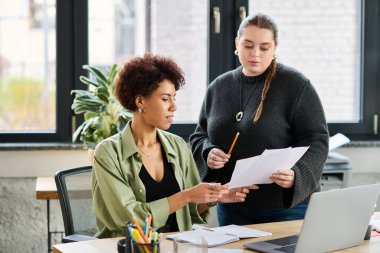 İki kadın dokümanları parlak, şık bir ofiste tartışıyor, takım çalışması ve çeşitlilik sergiliyorlar..