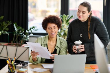 İki kadın yönetici parlak bir ofiste dokümanlar üzerinde verimli bir tartışmaya giriştiler..