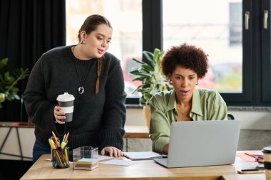 İki kadın yönetici birlikte dizüstü bilgisayarı incelerken verimli bir tartışmaya giriştiler..