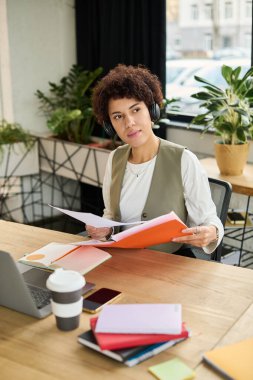 Genç bir Afrikalı Amerikalı kadın çalışkan bir ofiste çalışıyor, belgeleri inceliyor..