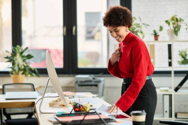 Azimli bir Afrikalı Amerikalı iş kadını masasında renkli belgeler düzenliyor..