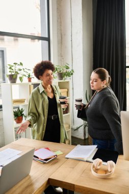 İki bayan yönetici kahvelerini içerken hararetle tartışıyorlar..