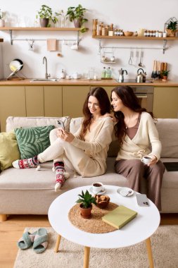 İkiz kardeşler birlikte rahatlar, kahkahalarını ve sohbetlerini yumuşak bir kanepede yudumlarken paylaşırlar..