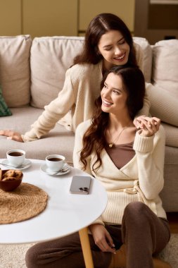 İki güzel ikiz kardeş evde kahve içerken keyifli bir sohbetin tadını çıkarıyorlar..