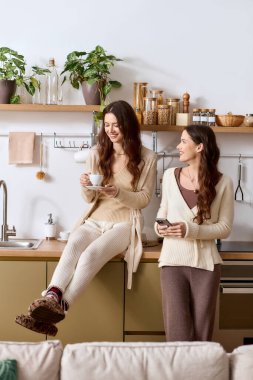 İkiz kardeşler şık bir mutfakta huzurlu bir gün geçirirken kahkaha ve sıcaklığı paylaşırlar..