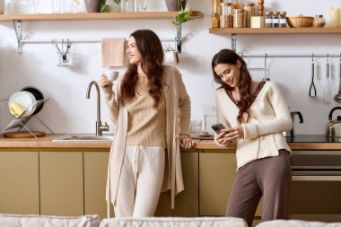 İkiz kardeşler neşeli bir öğleden sonrayı birlikte geçiriyorlar. Parlak mutfaklarında, bir içki içip sohbet ediyorlar..