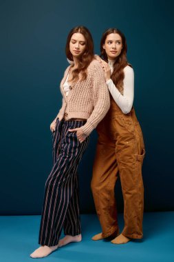 İkiz kardeşler benzersiz moda seçimlerini oyuncu ve kendinden emin bir duruşla sergilerler..