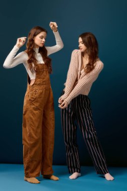 İkiz kardeşler neşelerini ve kahkahalarını canlı bir arka plana karşı şık kıyafetler giyip paylaşırlar..