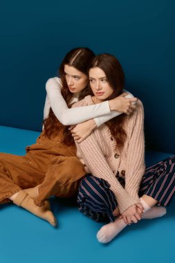 İkiz kardeşler yan yana oturur, neşe ve sevgi saçar sakin bir stüdyo ortamında..