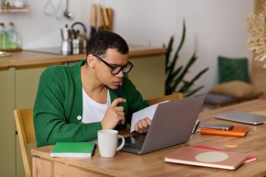 Odaklanmış ve düşünceli genç bir adam sıcak ve davetkar bir yuva ortamında özenle çalışıyor..