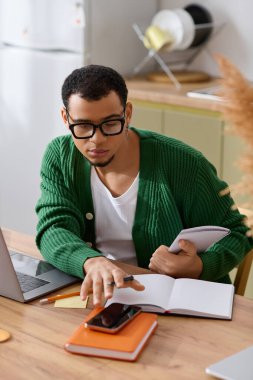 Rahat bir ortamda yakışıklı genç adam etrafı kitaplarla ve aletlerle çevriliyken işine odaklanıyor..