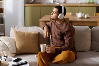 Rahat bir evde genç bir adam müzik dinlerken içkinin tadını çıkarıyor..