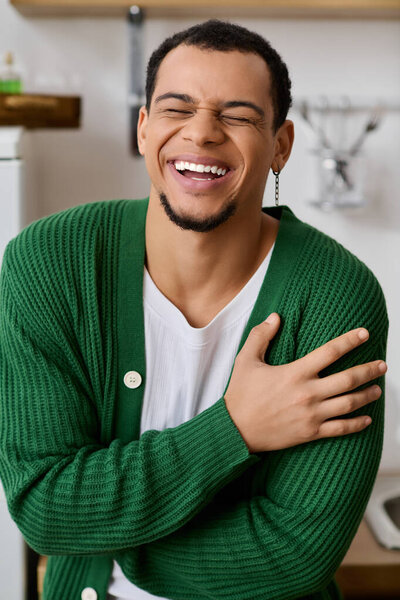 A cheerful young man enjoys a relaxed moment at home, sharing a heartfelt smile in his cozy attire.