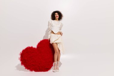 Genç Afro-Amerikan kadın canlı bir kırmızı kalp kutlamasının yanında kendine güvenerek poz veriyor..