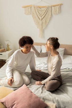 Huzurlu bir yatak odasında, sevgi dolu bir çift, yumuşak bir yatakta tatlı bir gülümseme paylaşır, samimiyetin tadını çıkarırlar..