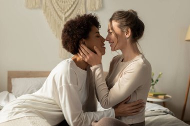 Sevgi dolu lezbiyen bir çift, huzurlu alanlarında neşe ve romantizm saçan samimi bir bakışı paylaşır..