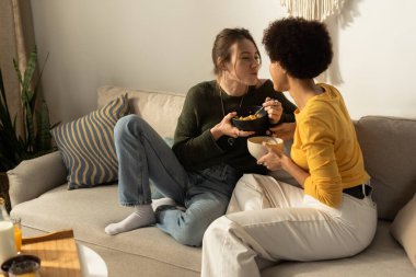 İki kadın, sıcak bir oturma odasında yemeğin tadını çıkarırken neşeyle bağlanıyorlar..