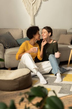 İki kadın neşeli bir anı paylaşıyor, sıcak ve davetkar bir mekanda birbirlerine eşlik ediyorlar..