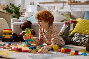 Neşeli bir çocuk parlak blokları yere yığıyor, rahat odasında yaratıcı oyunların keyfini çıkarıyor..