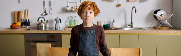 A cheerful boy stands proudly in a modern kitchen filled with bright colors and joyful warmth.