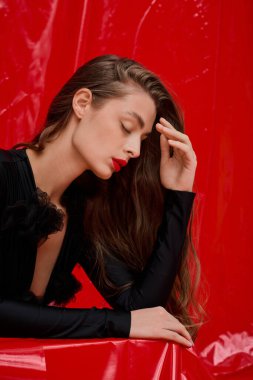 Göz kamaştırıcı genç bir kadın başını elinde tutuyor, çarpıcı bir ortamda stil ve güzellik yayıyor..