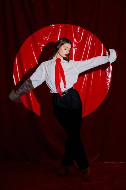 Zarif bir kadın dikkat çekici bir kırmızı dairenin önünde tarzını ve özgüvenini sergiliyor..