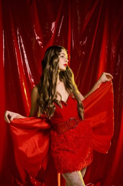Güzel, genç bir kadın moda anlayışını göz kamaştırıcı kırmızı bir elbiseyle sergiliyor. Kendine güveni tam..