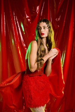 Genç bir kadın çarpıcı kırmızı bir elbiseyle zarif bir şekilde poz veriyor..