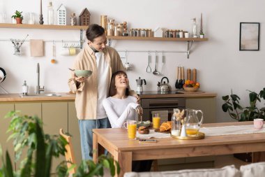 Bir adam ortağına kahvaltı servisi yapar onlar da sıcak mutfaklarında keyifli anlarını paylaşırlar..