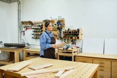 Yetenekli genç bir kadın, aletler ve odunlarla çevrili bir davet atölyesinde özenle çalışıyor..