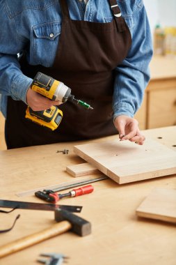 Genç bir kadın, canlı bir atölyede çalışırken matkabı ustalıkla kullanıyor..